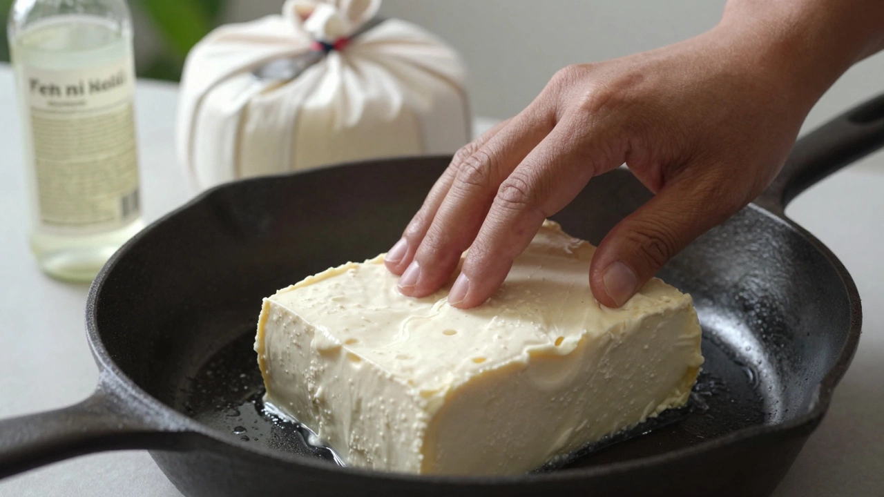 A block of paneer being pressed under a cast iron pan with vinegar bottle nearby.